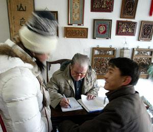 A young man and his girlfriend hover impatiently as an elderly man scribbles on a sheet of paper -- awaiting not a fortune, but a new name, at a licensed shop located near a Beijing Buddhist temple.<b