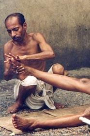 A trained masseurs giving an oil massage at a "ghat" (platform constructed on the river bank) in Varanasi. These masseurs ply their trade at "ghats" in religious places, where people throng to worship in the river, a custom that has been prevalent for centuries. These masseurs, it is believed, can cure all kinds of aches, pains and minor ailments.