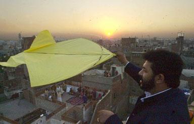 A man flies a kite at sunset after a day-long kite flying festival, locally known as 'Basant', in Pakistan's eastern city of Lahore, 09 February 2003, as officials said around 100,000 people from inside and outside the country had arrived in the city to celebrate the occasion. Two people died and more than 100 were injured during the annual kite flying festival marking the advent of spring in Pakistan. Public parks and rooftops were crowded with revellers celebrating the festival which started with music concerts and dinner parties organized privately or as public events late Saturday.