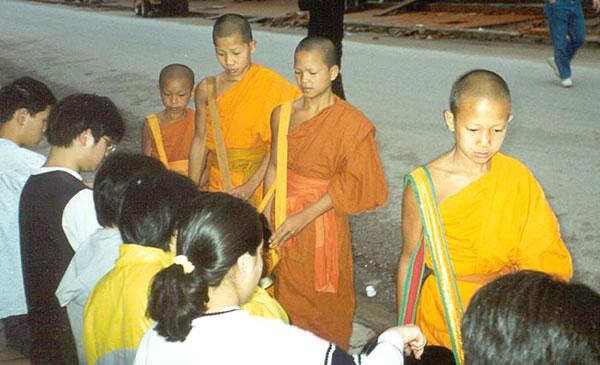 Young novice monks make their early morning alms rounds through the streets of Luang Prabang.