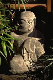 Nestled in a quiet corner of this tiny private garden, a stone Buddha adds an element of contemplative serenity.