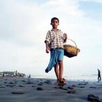 A young coral vendor walks a long the beach as he looks for customers in Coxbazar, 20 August 2002. Hundreds of children sell their wares to local and foreign tourist to earn a living.