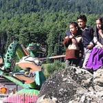 Two Kashmiri brothers and their twin sisters sit on a rock looking at rides inside Kashmir's first amusement park in Pahalgam.