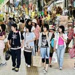 Young tourists stroll on the main shopping street in Naha, Okinawa Prefecture, Japan.