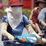 A masked woman wearing long gloves rides a motorcycle in Hanoi. Beauty in the minds of most Vietnamese women means white skin-a symbol of feminity, pureness, sophistication and high social class.