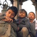 Three children perch on a stone lion in Durbar Square, Patan.