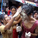 A young Thai girl rubs talcum powder mixed with water onto the face of a reveller during the Thai New Year or Songkran celebrations. Bangkok residents take to the streets in friendly water battles to start celebrations for the Thai Buddhist New Year (in 2003, we enter the Thai year 2546.)