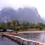 A not-so-secure looking bridge leads to a group of mist-shrouded mountains in Vang Vieng.